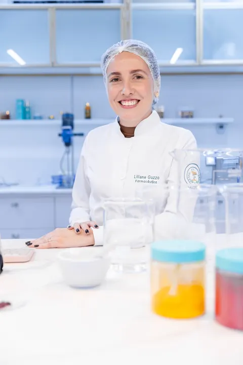 Liliane Guzzo no laboratório, de jaleco e touca